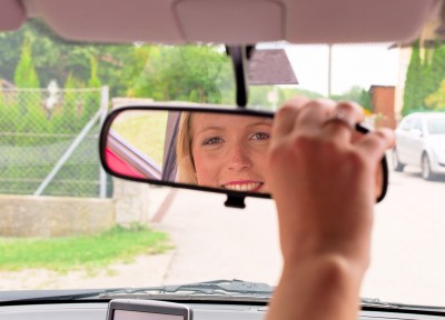 fahrtraining freundlich lächelnde Frau im Rückspiegel